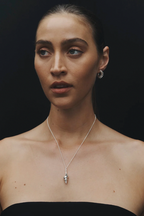 Woman wearing a necklace with a black background